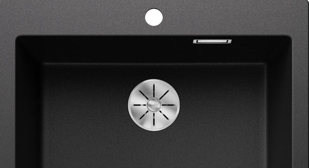 Czarny zlewozmywak z okrągłym odpływem ze stali nierdzewnej i otworem na baterię. W górnej części widoczny jest prostokątny otwór przelewowy.