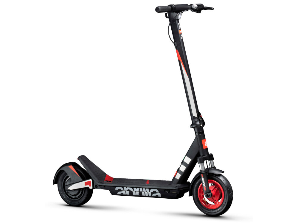 Czarno-czerwona hulajnoga elektryczna z widocznym logo \'aprilia\' na podeście. Posiada amortyzację i 10-calowe koła.