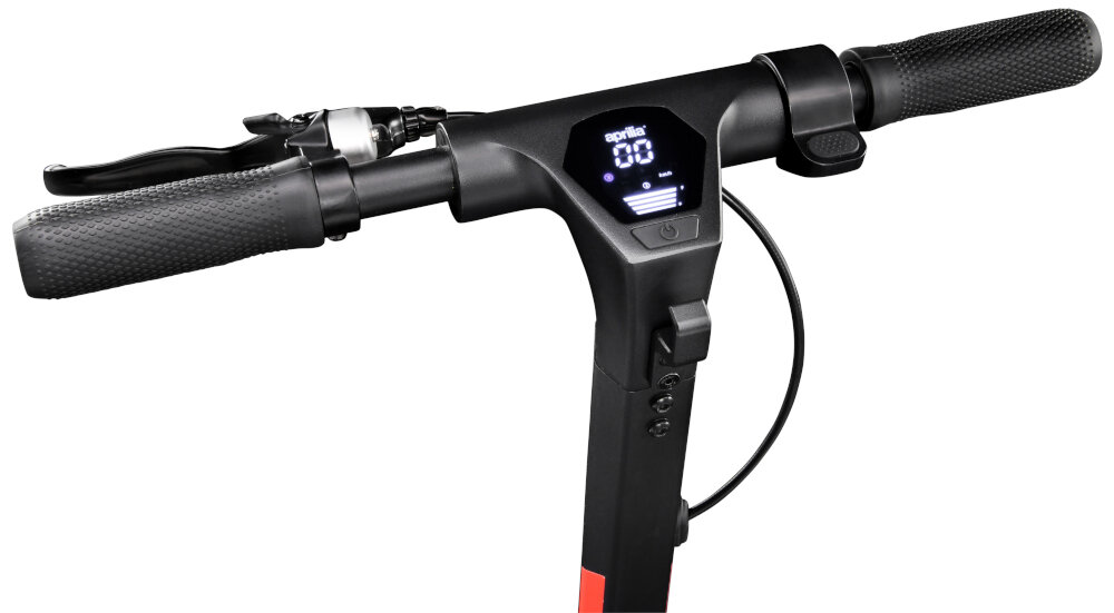 Kierownica hulajnogi elektrycznej z wyświetlaczem pokazującym prędkość i poziom naładowania baterii. Rączki są czarne z teksturowanym uchwytem, a na wyświetlaczu widoczny jest napis \'aprilia\'.