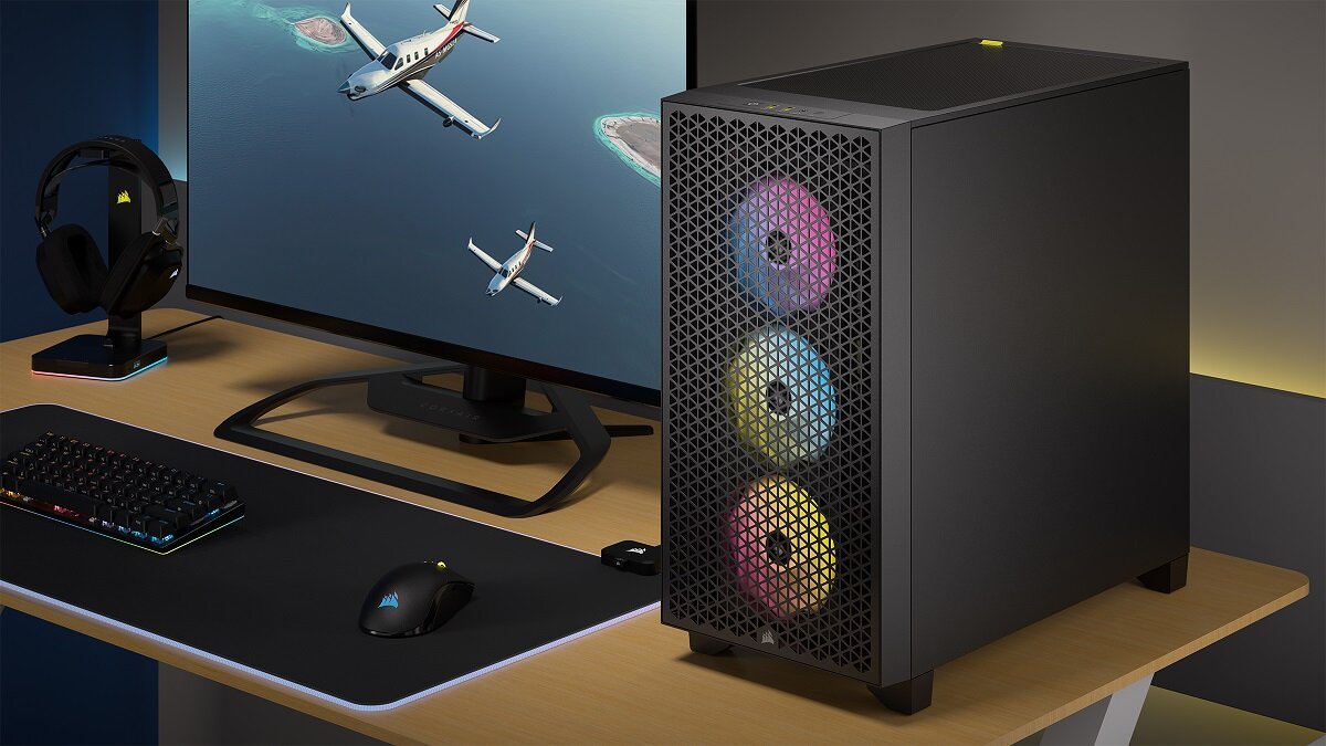 Na biurku znajduje się czarna obudowa komputerowa z trzema podświetlanymi wentylatorami z przodu. Obok widoczny jest monitor z obrazem samolotu, klawiatura, myszka i słuchawki.