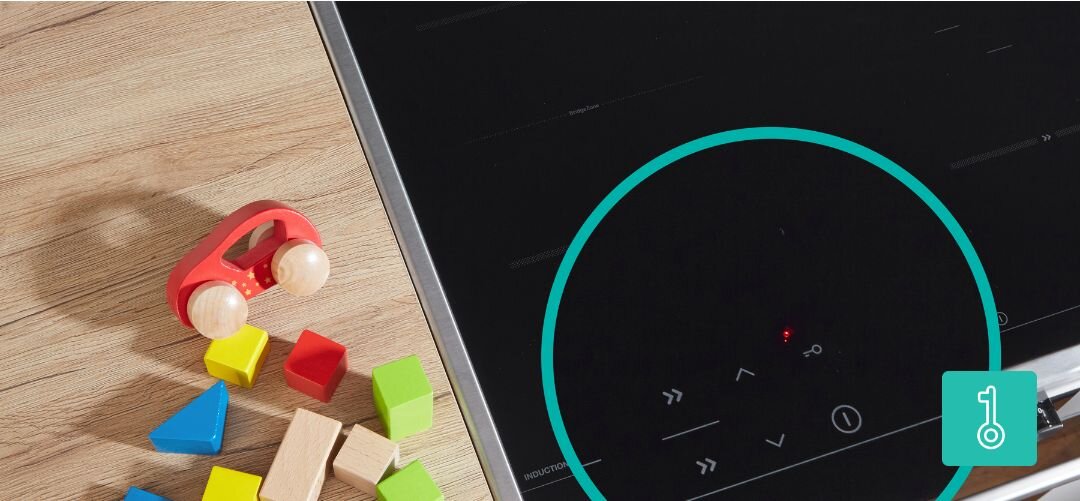 KUCHNIA GORENJE MEKIS5101I Fragment czarnej płyty indukcyjnej na drewnianym blacie, obok której leżą kolorowe drewniane klocki i czerwony drewniany samochodzik, a powiększone koło po prawej stronie podkreśla panel sterowania z ikoną blokady, symbolizując funkcję zabezpieczenia przed dziećmi ChildLock blokada dzieci ochrona bezpieczeństwo