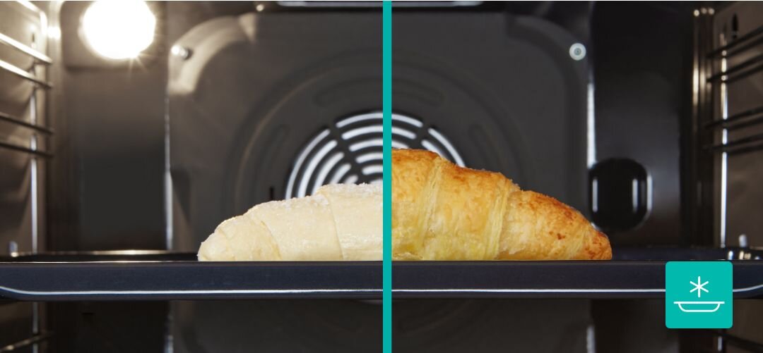 KUCHNIA GORENJE MEKIS5101I Wnętrze piekarnika pokazane w przekroju z jedną rogalikową bułką na blasze, po lewej stronie widoczny jest surowy jasny rogalik, a po prawej ten sam wypiek już zarumieniony i upieczony, co ilustruje efekt delikatnego podgrzewania lub rozmrażania FrozenBake do mrożonek