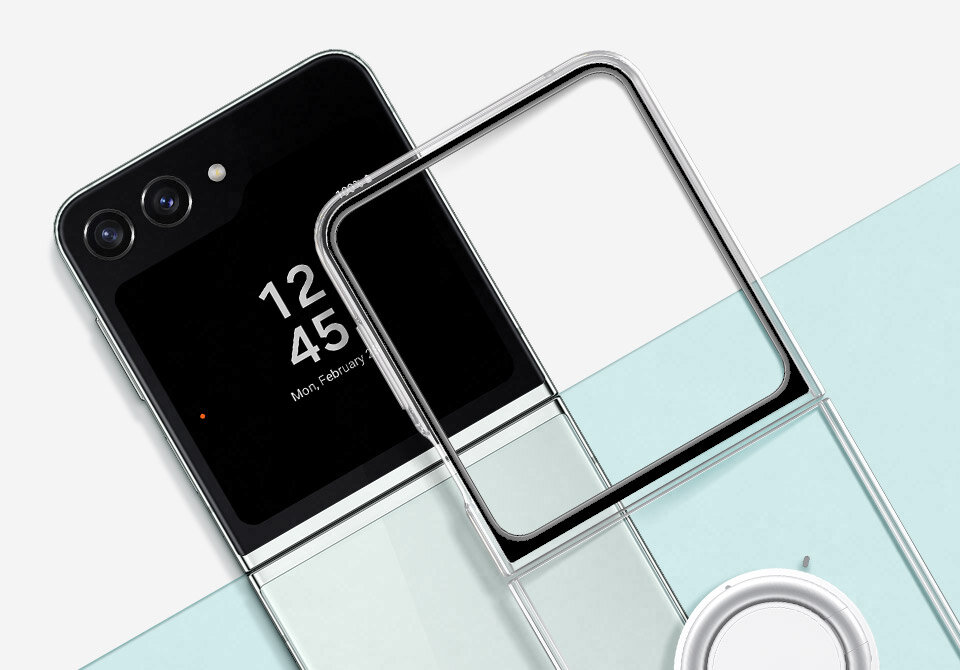 Smartfon z widocznym ekranem, na którym wyświetlana jest godzina 12:45 i data \'Mon, February\'. Obok znajduje się przezroczyste etui i okrągły element, prawdopodobnie uchwyt lub ładowarka.