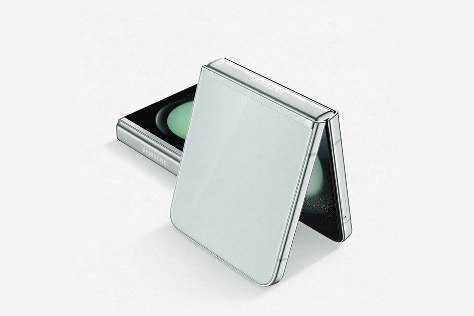 Na obrazie widoczny jest składany smartfon w kolorze grafitowym z logo \'SAMSUNG\' na obudowie. Urządzenie jest częściowo otwarte, ukazując ekran i zawias.