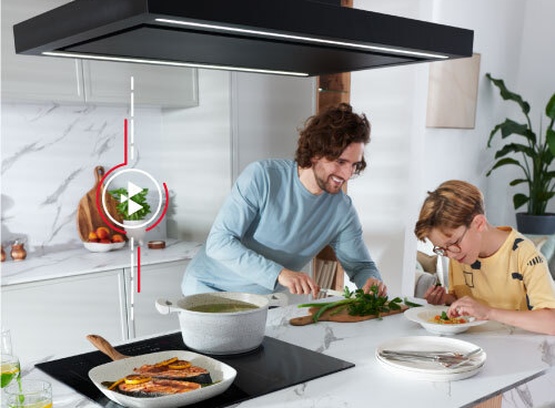 Kuchnia z nowoczesnym okapem i płytą grzewczą, na której stoją garnki. W tle widoczne są marmurowe ściany i drewniane elementy dekoracyjne.