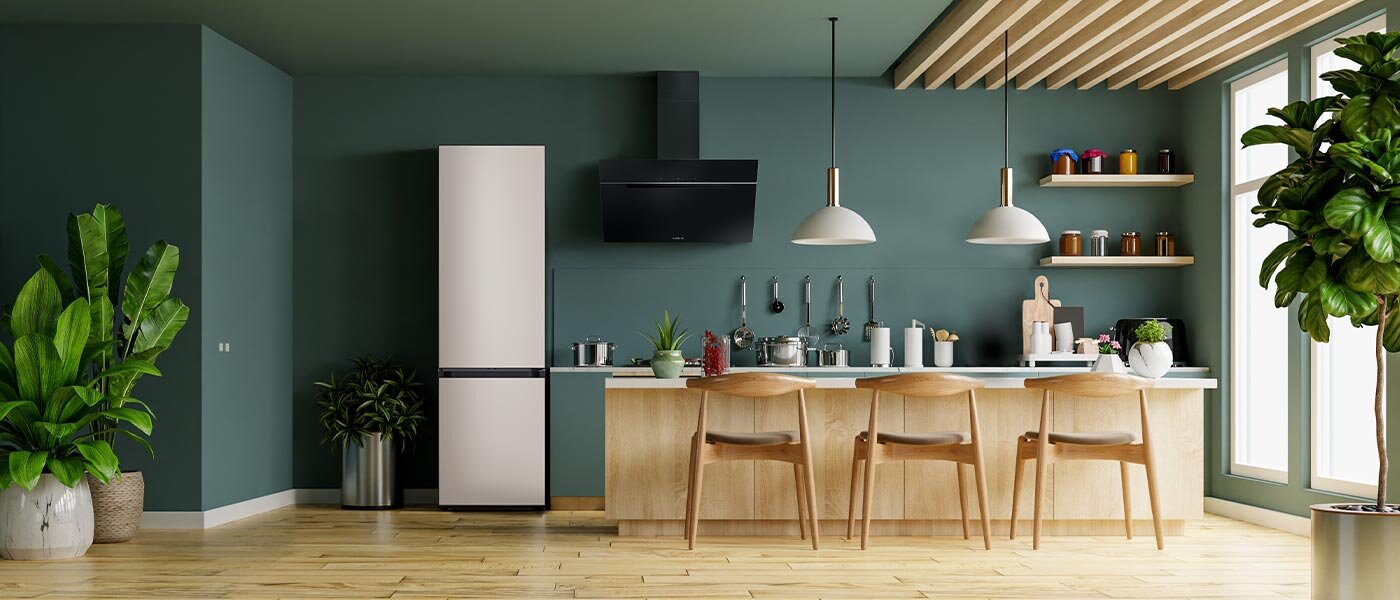 Kuchnia z lodówką w zabudowie, drewnianym blatem i czterema krzesłami. Na blacie znajdują się różne akcesoria kuchenne, a w tle widać rośliny i półki z pojemnikami.