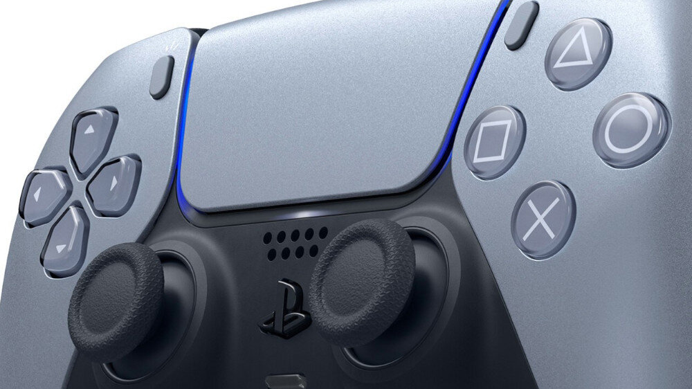 Srebrny kontroler do gier z widocznymi przyciskami i analogowymi drążkami. Na kontrolerze znajduje się logo w kształcie litery \'P\'.