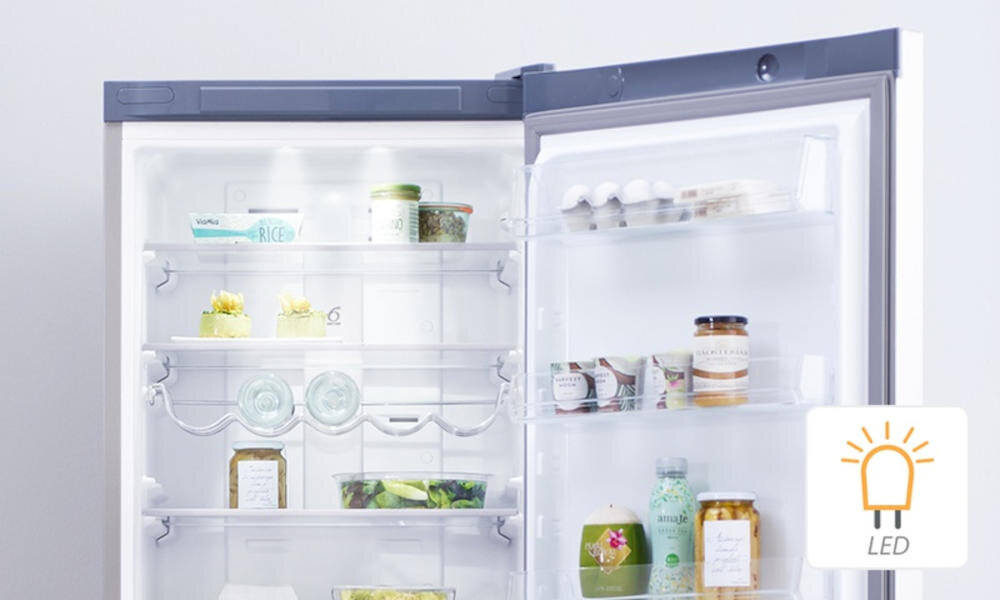 Otwarta lodówka z widocznymi półkami, na których znajdują się różne produkty spożywcze. W prawym dolnym rogu znajduje się ikona z symbolem żarówki i napisem \'LED\'.