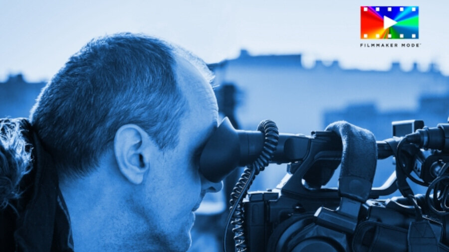 Osoba patrzy przez wizjer kamery, a w prawym górnym rogu widoczne jest kolorowe logo z napisem \'FILMMAKER MODE\'.