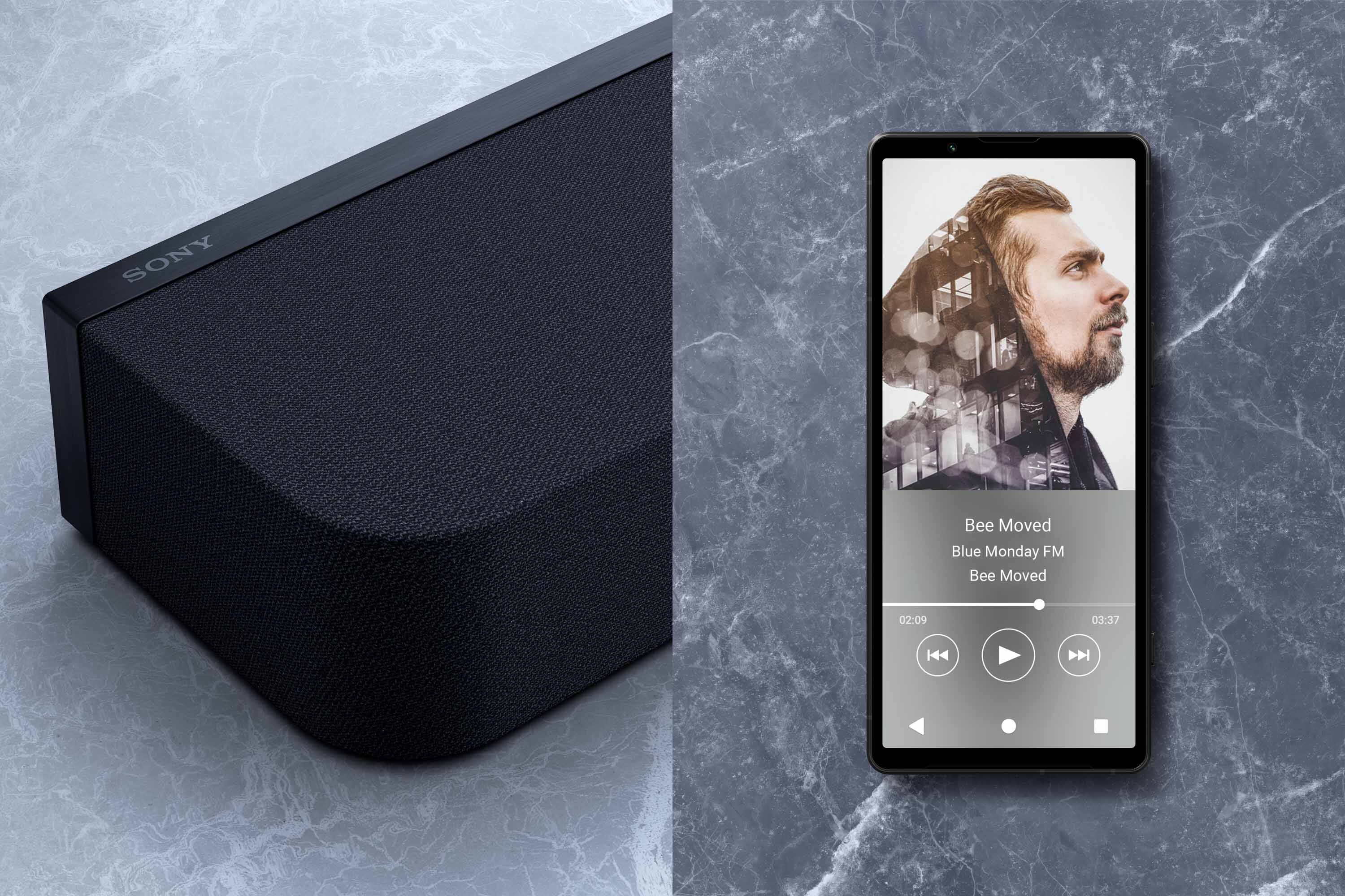 Po lewej stronie widoczny jest czarny soundbar z logo \'SONY\' na górnej krawędzi. Po prawej stronie znajduje się smartfon z wyświetlaczem pokazującym odtwarzacz muzyki z utworem \'Bee Moved\' i zdjęciem mężczyzny.