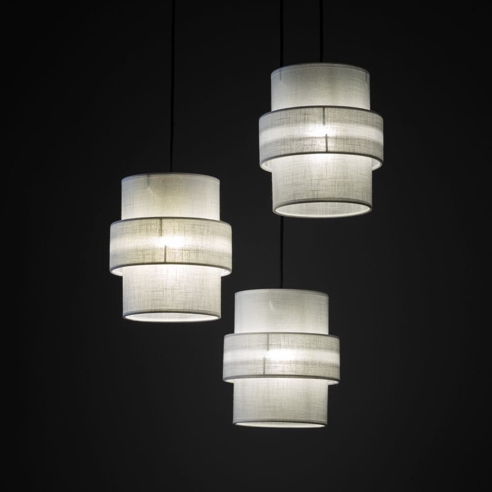 Trzy wiszące lampy o cylindrycznym kształcie, wykonane z białego materiału, emitują delikatne światło. Lampy zawieszone są na ciemnym tle, co podkreśla ich jasność.