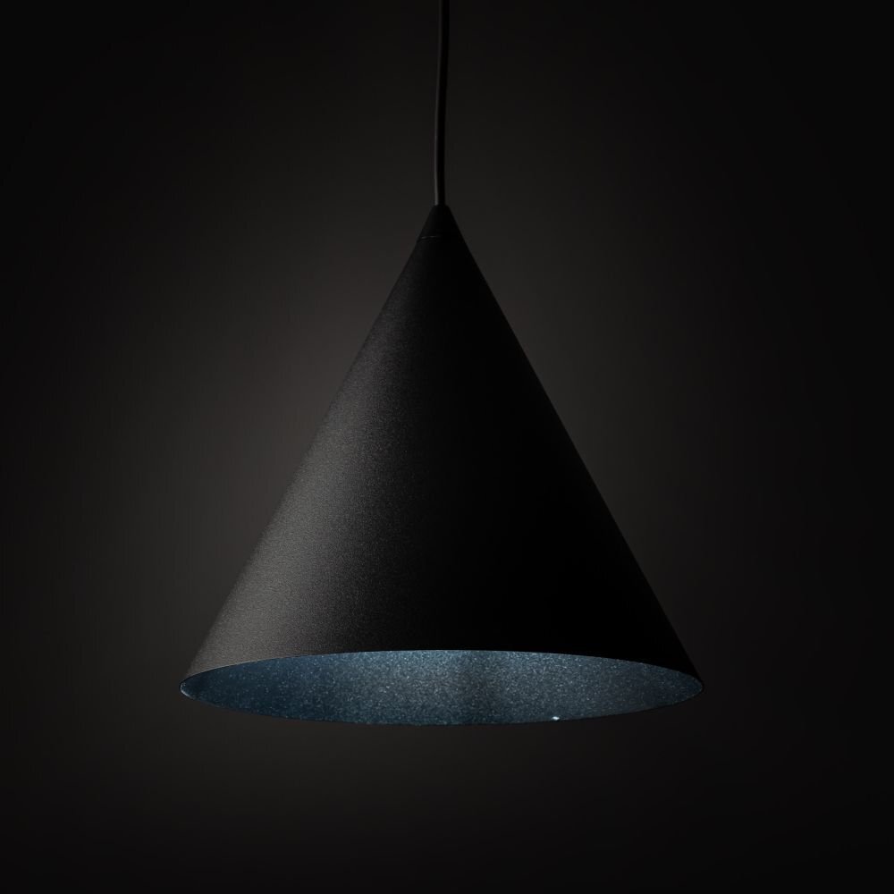 Czarna, stożkowa lampa wisząca z metalowym kloszem, zawieszona na cienkim przewodzie. Wnętrze klosza jest jasne, co kontrastuje z ciemnym otoczeniem.