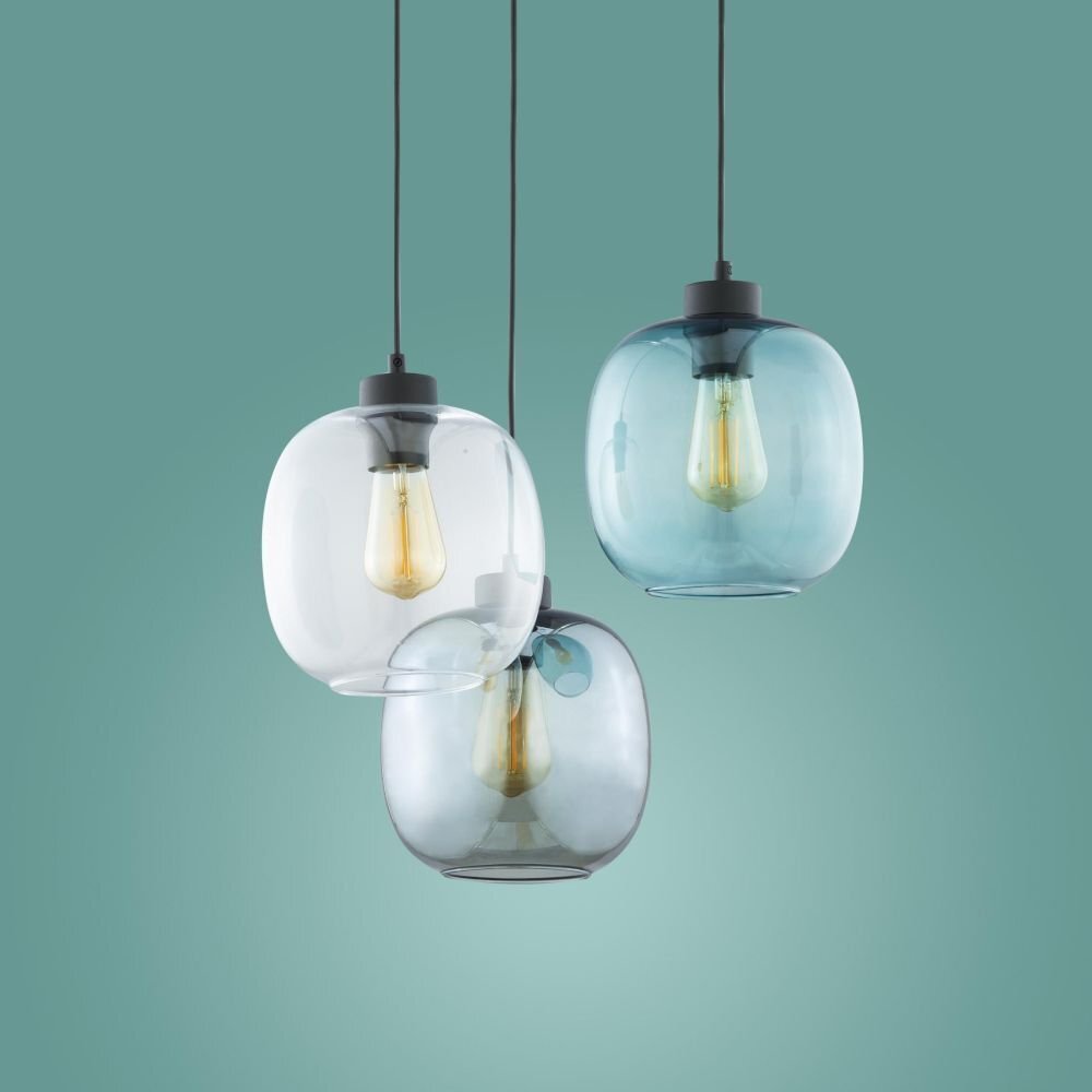 Trzy wiszące lampy z przezroczystymi kloszami w odcieniach czerni i niebieskiego, każda z widoczną żarówką wewnątrz. Lampy zawieszone są na czarnych przewodach na tle zielonej ściany.