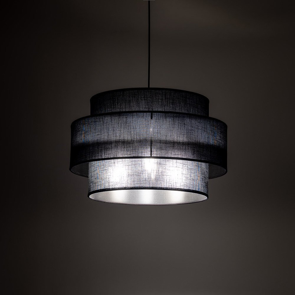 Czarna lampa wisząca z trzema okrągłymi abażurami, emitująca jasne światło. Lampa zawieszona jest na ciemnym tle, co podkreśla jej nowoczesny design.