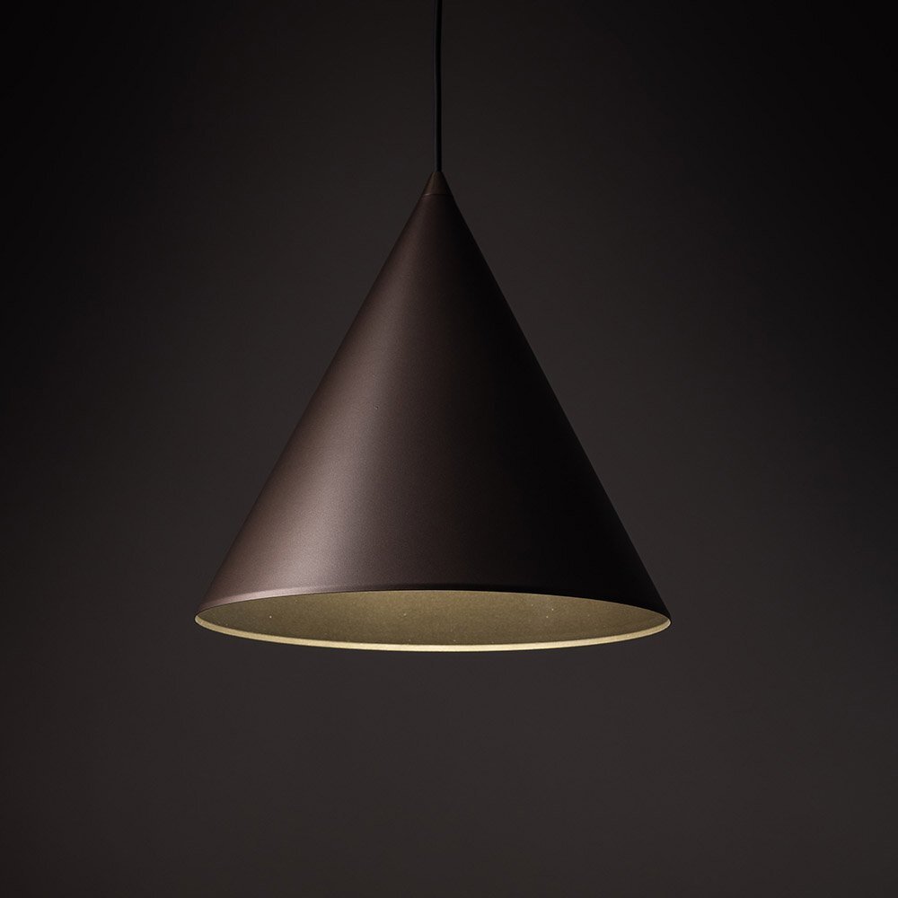 Brązowa, stożkowa lampa wisząca z metalowym kloszem na ciemnym tle. Lampa ma gładką powierzchnię i jest zawieszona na cienkim przewodzie.