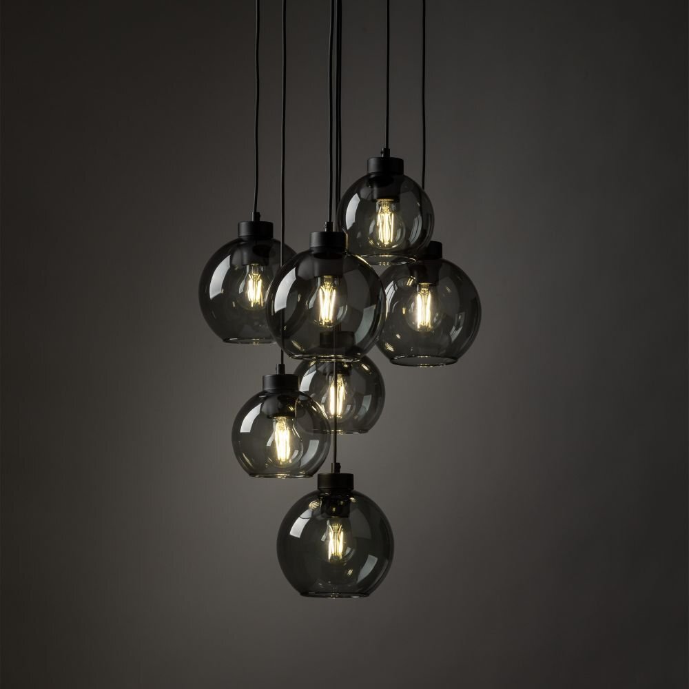 Lampa wisząca z siedmioma szklanymi kloszami w kształcie kul, zawieszona na czarnych przewodach. Klosze są grafitowe, a wewnątrz widoczne są żarówki emitujące ciepłe światło.