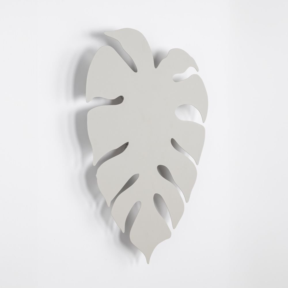 Beżowy kinkiet ścienny w kształcie liścia monstery z wycięciami, wykonany z gładkiego materiału. Lampa ma nowoczesny design i jest przeznaczona do montażu na ścianie.
