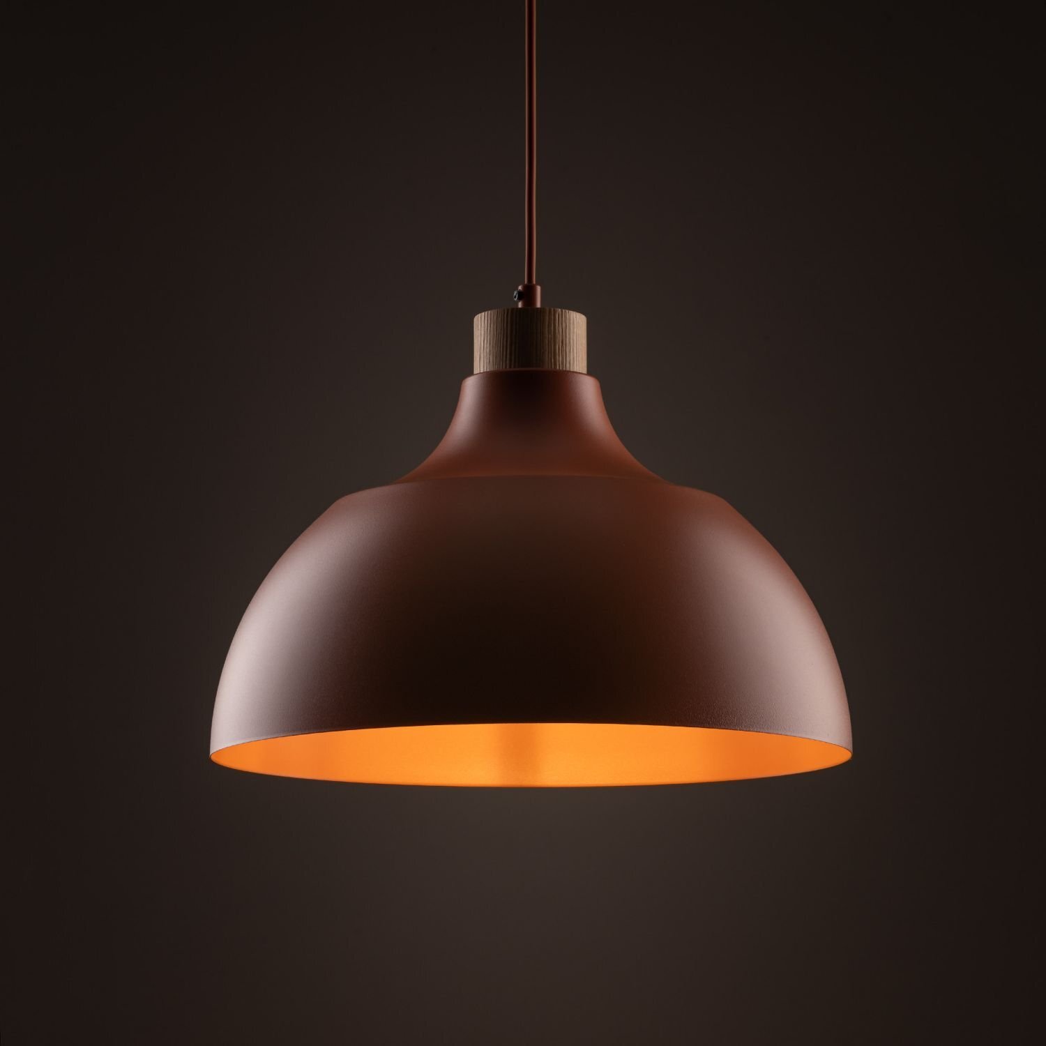 Lampa wisząca w kolorze ceglastym z metalowym kloszem i drewnianym elementem przy zawieszeniu. Wnętrze klosza jest jasne, co podkreśla jego kształt.