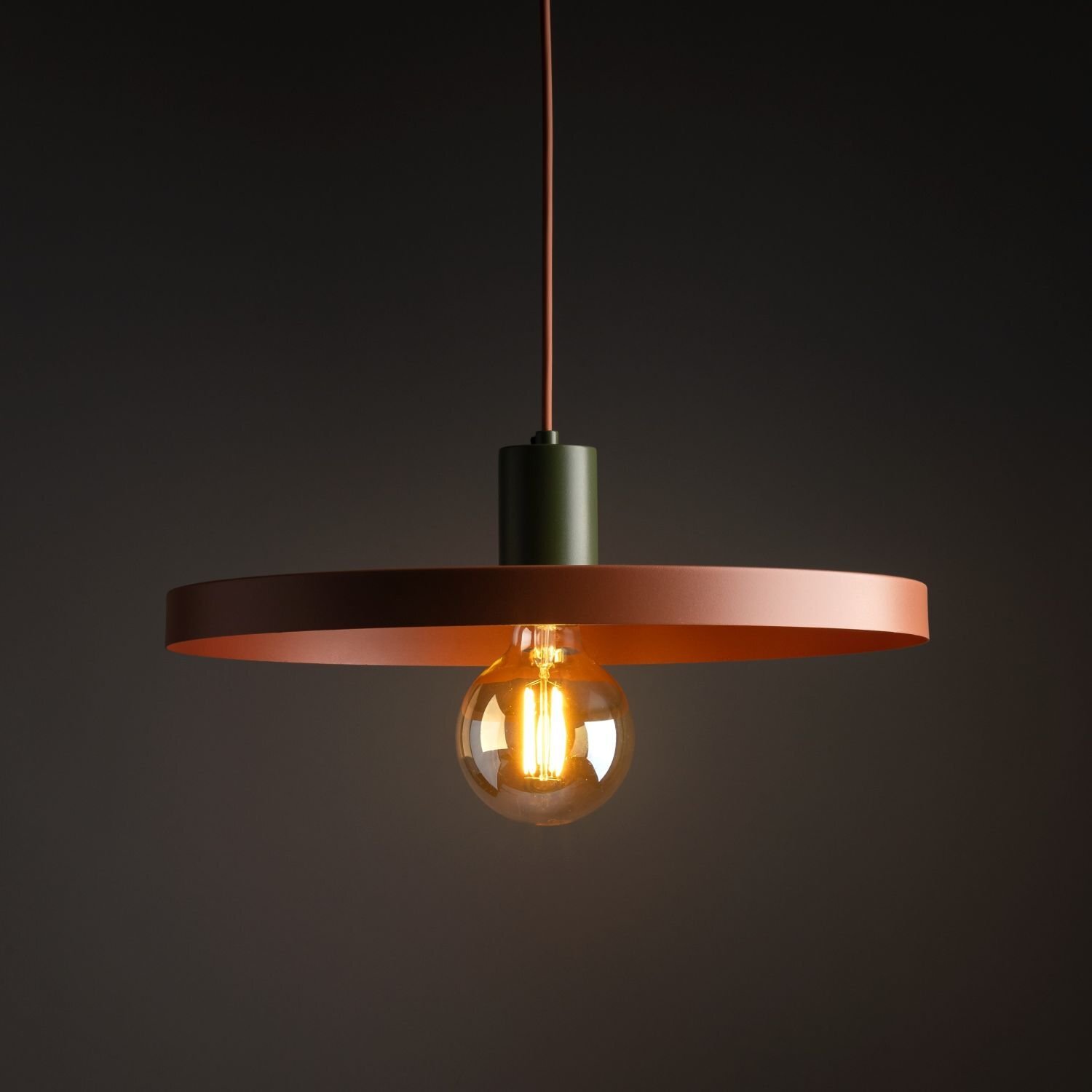 Lampa wisząca z metalowym kloszem w kolorze miedzianym, z widoczną żarówką E27. Klosz ma prosty, okrągły kształt i jest zawieszony na ciemnym przewodzie.