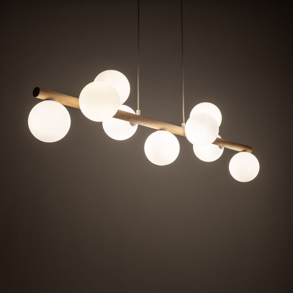 Lampa wisząca z drewnianym elementem, na którym zamocowane są kuliste, białe klosze. Lampa jest zawieszona na kilku cienkich przewodach.