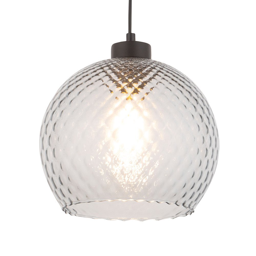 Szklana lampa wisząca o kulistym kształcie z fakturą w formie wypukłych wzorów. Emituje ciepłe światło, a jej górna część jest czarna.