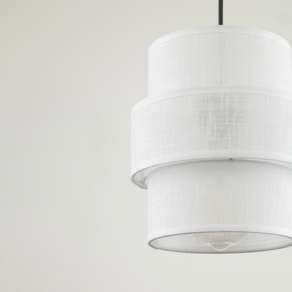 Biała lampa wisząca z dwoma cylindrycznymi kloszami wykonanymi z materiału o teksturze przypominającej tkaninę. Lampa zawieszona jest na czarnym przewodzie.