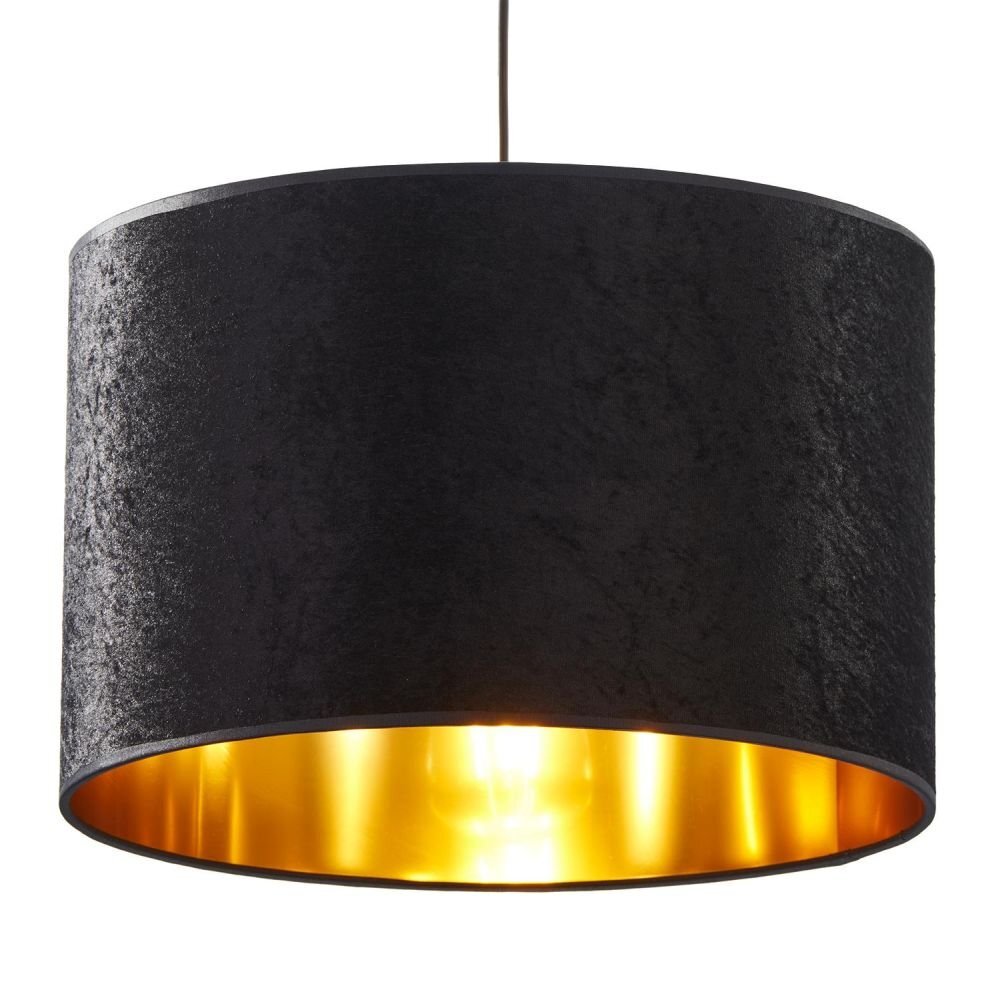Czarna lampa wisząca z cylindrycznym kloszem, którego wnętrze jest złote. Lampa jest zawieszona na cienkim przewodzie.
