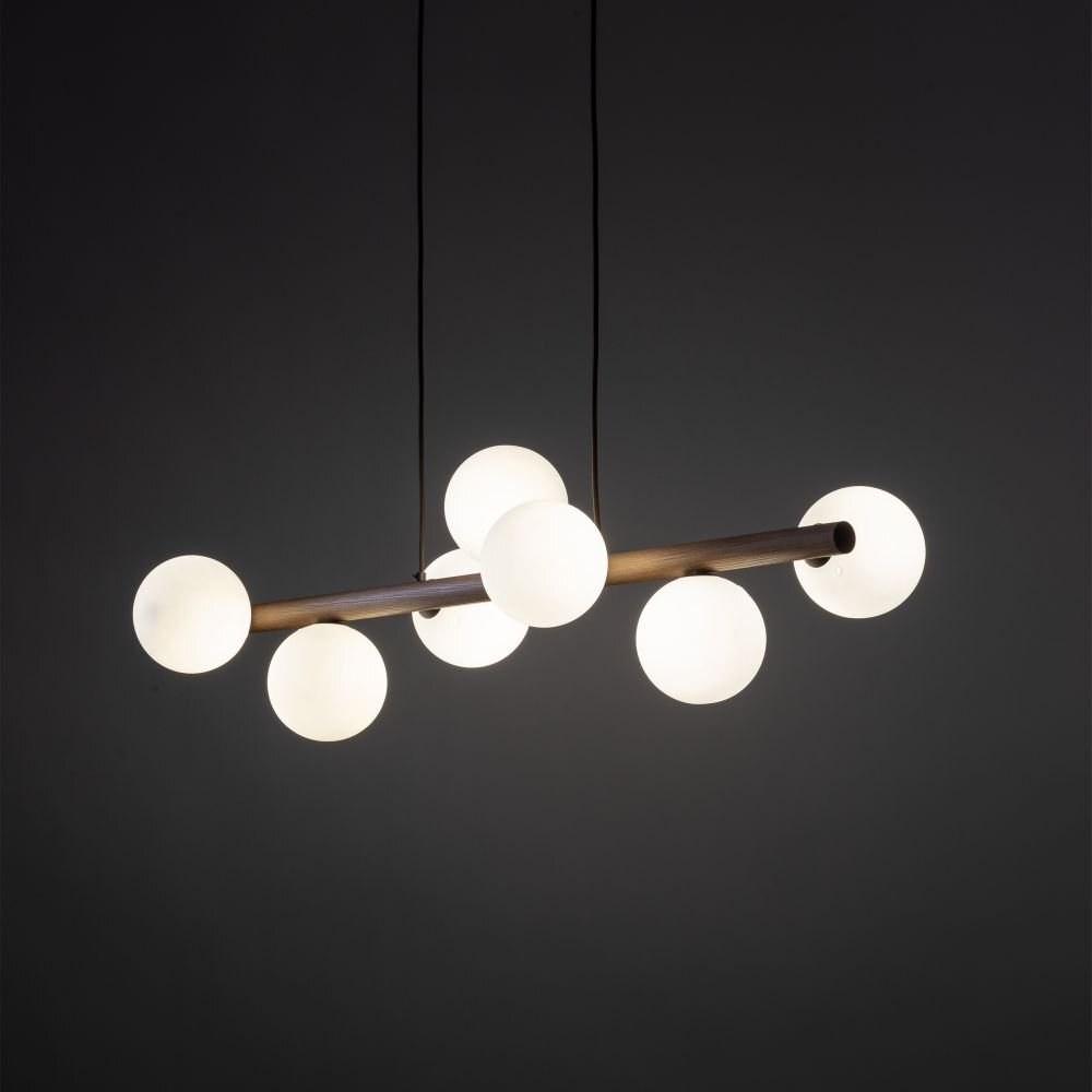 Lampa wisząca z siedmioma kulistymi kloszami zamontowanymi na drewnianym ramieniu. Klosze są białe, a całość zawieszona jest na dwóch czarnych przewodach.