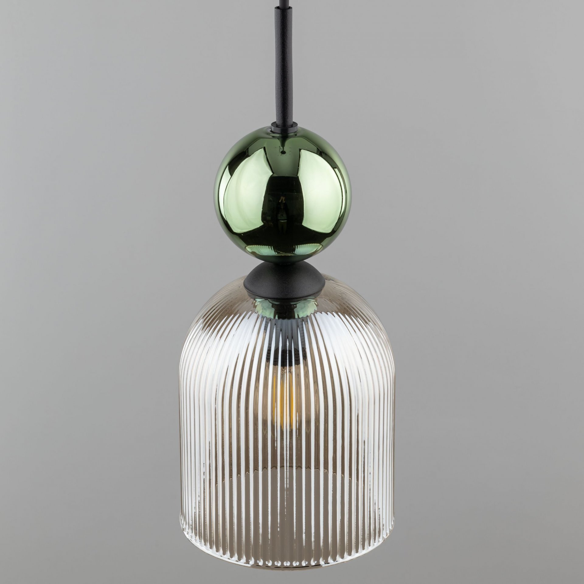 Lampa wisząca z zielono-bursztynowym szklanym kloszem o żebrowanej strukturze. Górna część lampy ma kulisty, zielony element dekoracyjny.