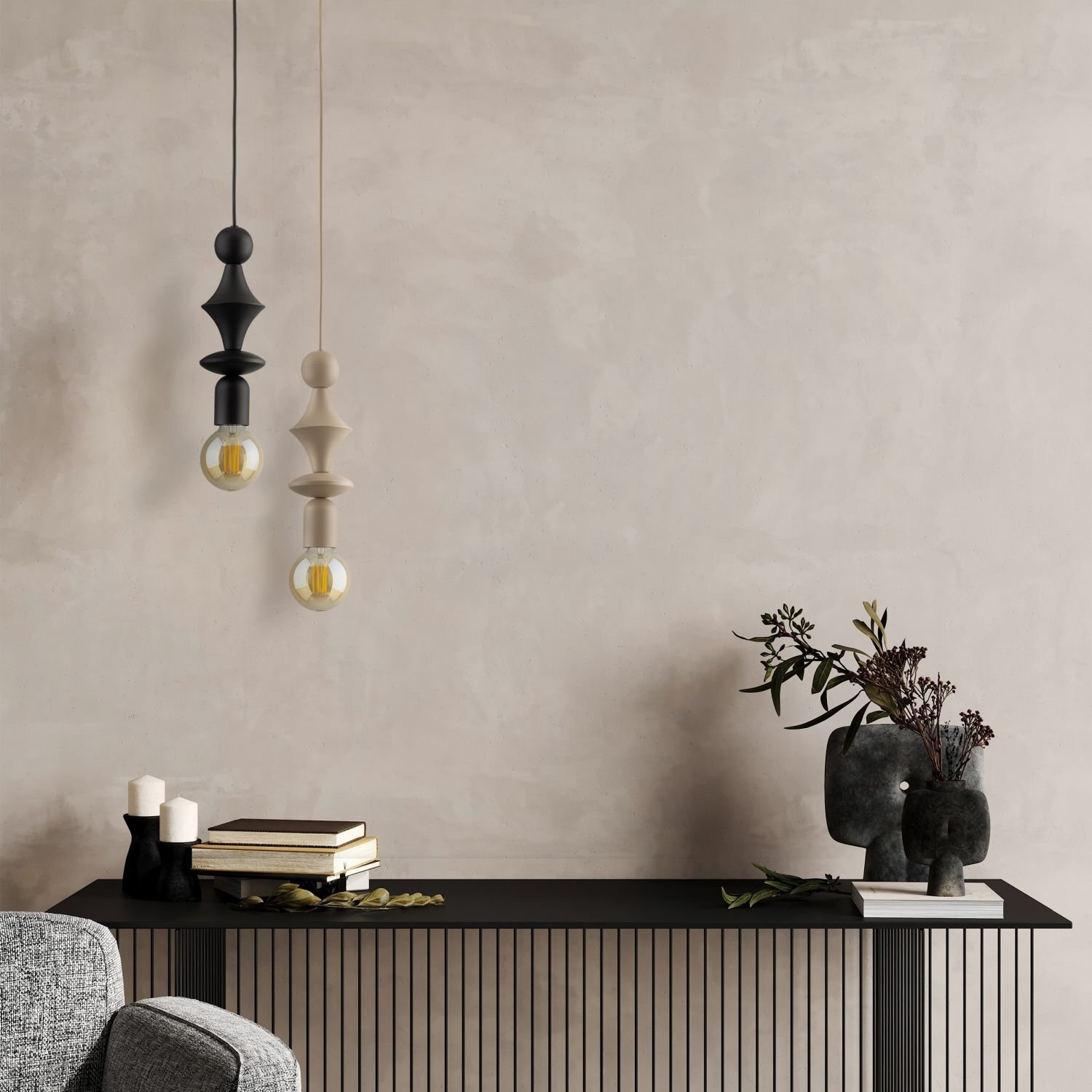 Na obrazie widoczne są dwie wiszące lampy o nowoczesnym designie, jedna czarna, druga beżowa, z żarówkami na końcu. W tle znajduje się minimalistyczna konsola z książkami, świecami i dekoracyjną rośliną w ciemnej donicy.