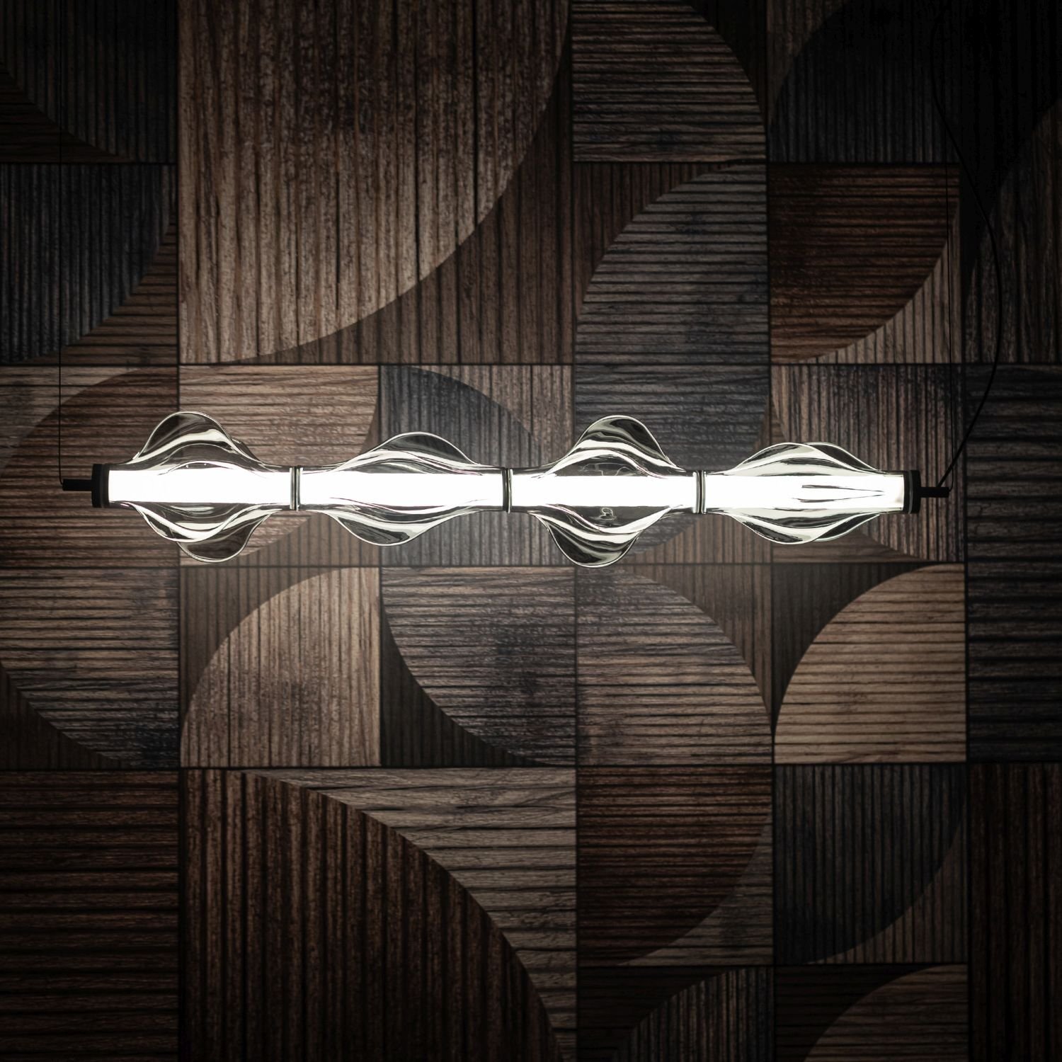 Lampa wisząca LED o nowoczesnym designie z czarnymi elementami i przezroczystymi kloszami, emitująca jasne światło. W tle widoczna jest ściana z drewnianymi panelami o geometrycznym wzorze.