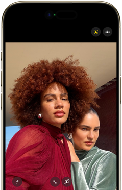 Na ekranie smartfona widoczne są dwie osoby w kolorowych ubraniach. Na górze ekranu znajdują się ikony aplikacji fotograficznej.