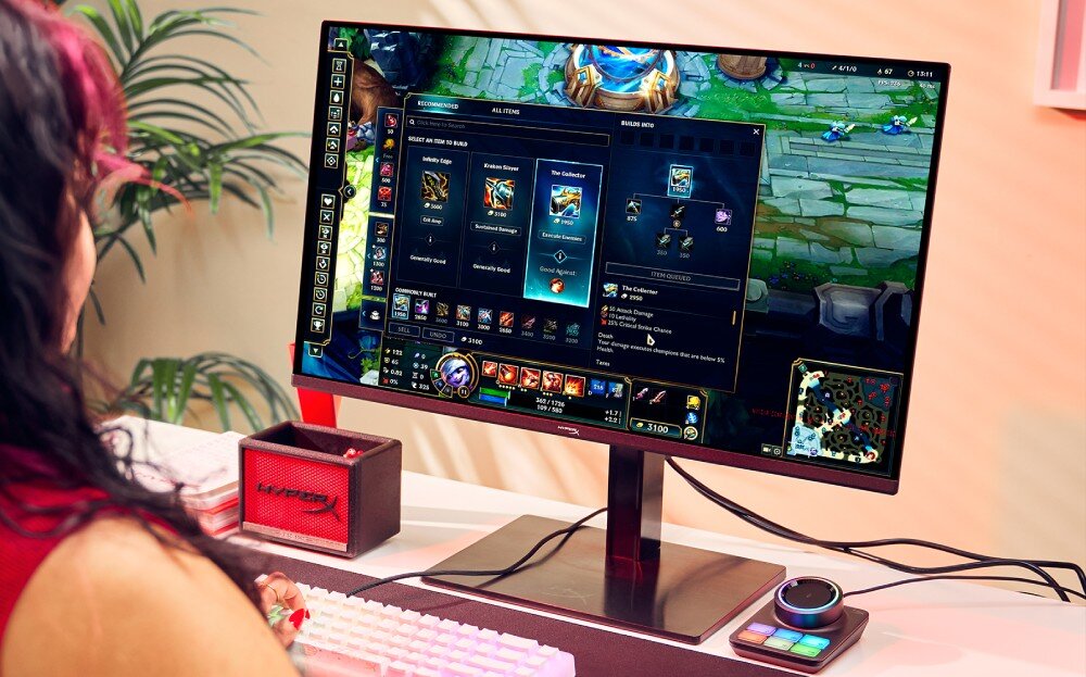 Monitor HYPERX Omen 27q Osoba grająca w 'League of Legends' na monitorze z widocznym kontrolerem audio obok klawiatury