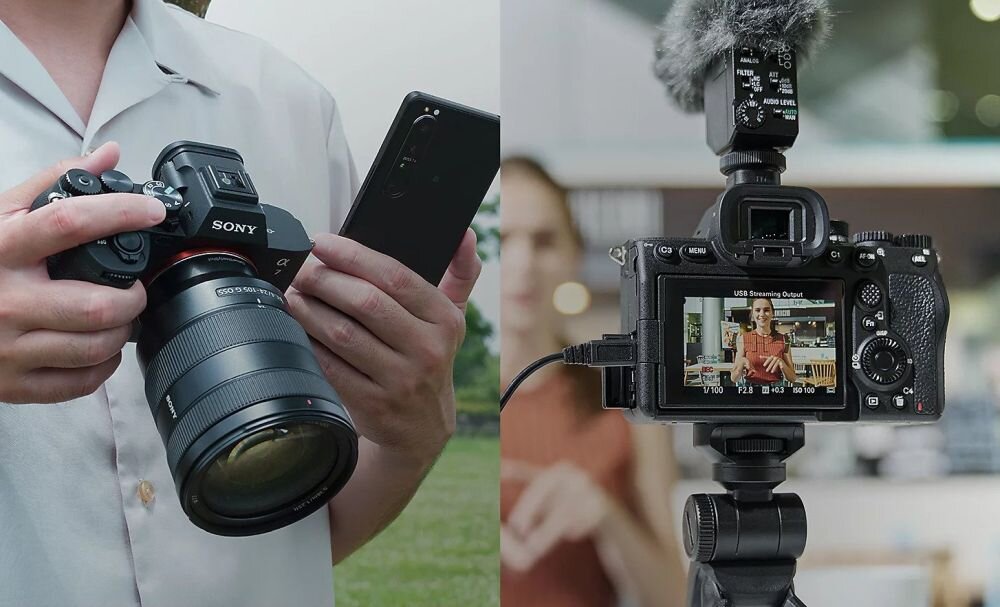 Po lewej stronie osoba trzyma aparat bezlusterkowy marki SONY z dużym obiektywem i smartfonem. Po prawej stronie widoczny jest tył aparatu z ekranem wyświetlającym obraz nagrywanej osoby oraz mikrofon zamontowany na górze.