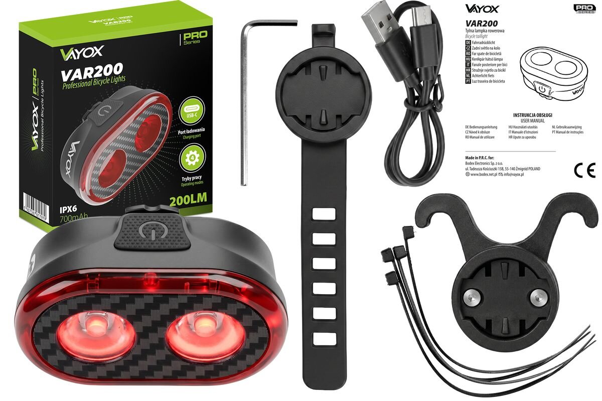 Na obrazie znajduje się lampka rowerowa z dwoma czerwonymi światłami, opakowanie z napisem \'VAYOX VAR200 Professional Bicycle Lights\', oraz akcesoria montażowe i kabel USB. Widoczna jest także instrukcja obsługi i logo VAYOX.