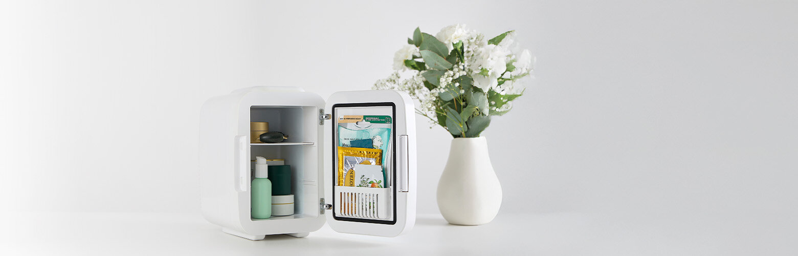 Chłodziarka kosmetyczna MPM-04-CK-01 wypełniona kosmetykami. Obok wazon z kwiatami.
