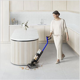 Osoba używa elektrycznego mopa na jasnej podłodze w nowoczesnej kuchni. Mop zbiera rozlane płyny i drobne zanieczyszczenia.