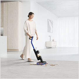 Osoba używa elektrycznego mopa na jasnej podłodze, usuwając rozsypane resztki. W tle widoczne są minimalistyczne meble i dekoracje.