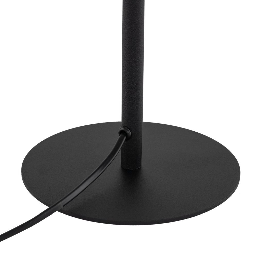 Czarna, okrągła podstawa lampki z wystającym kablem z boku. Kabel jest przymocowany do pionowego elementu lampki.