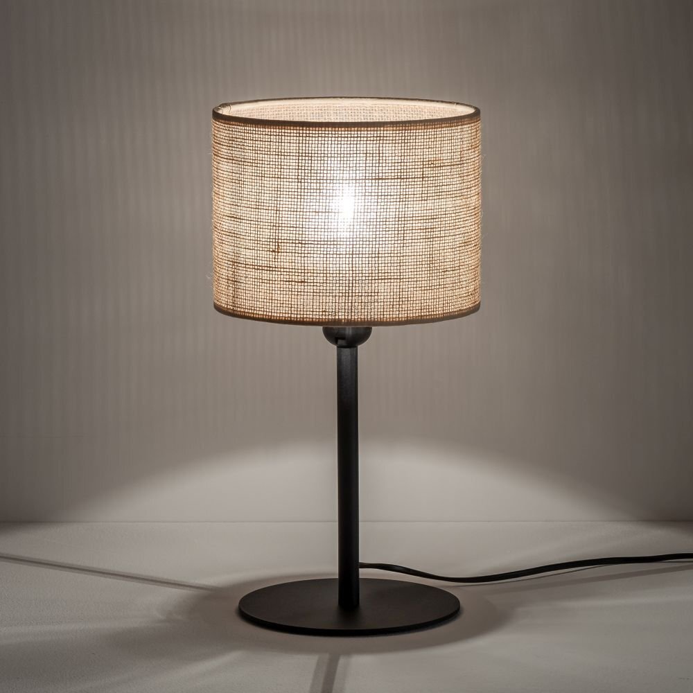 Lampa stołowa z beżowym abażurem z juty i czarną podstawą. Lampa stoi na płaskiej powierzchni, a w tle widać delikatne cienie.