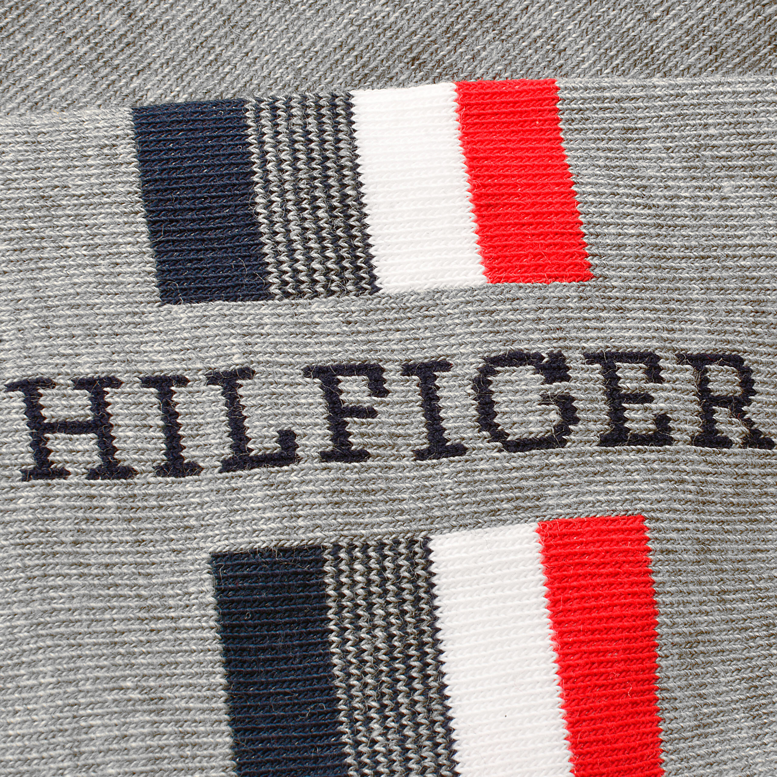 Szary materiał z widocznym napisem \'HILFIGER\' oraz wzorem w kolorach granatowym, białym i czerwonym.