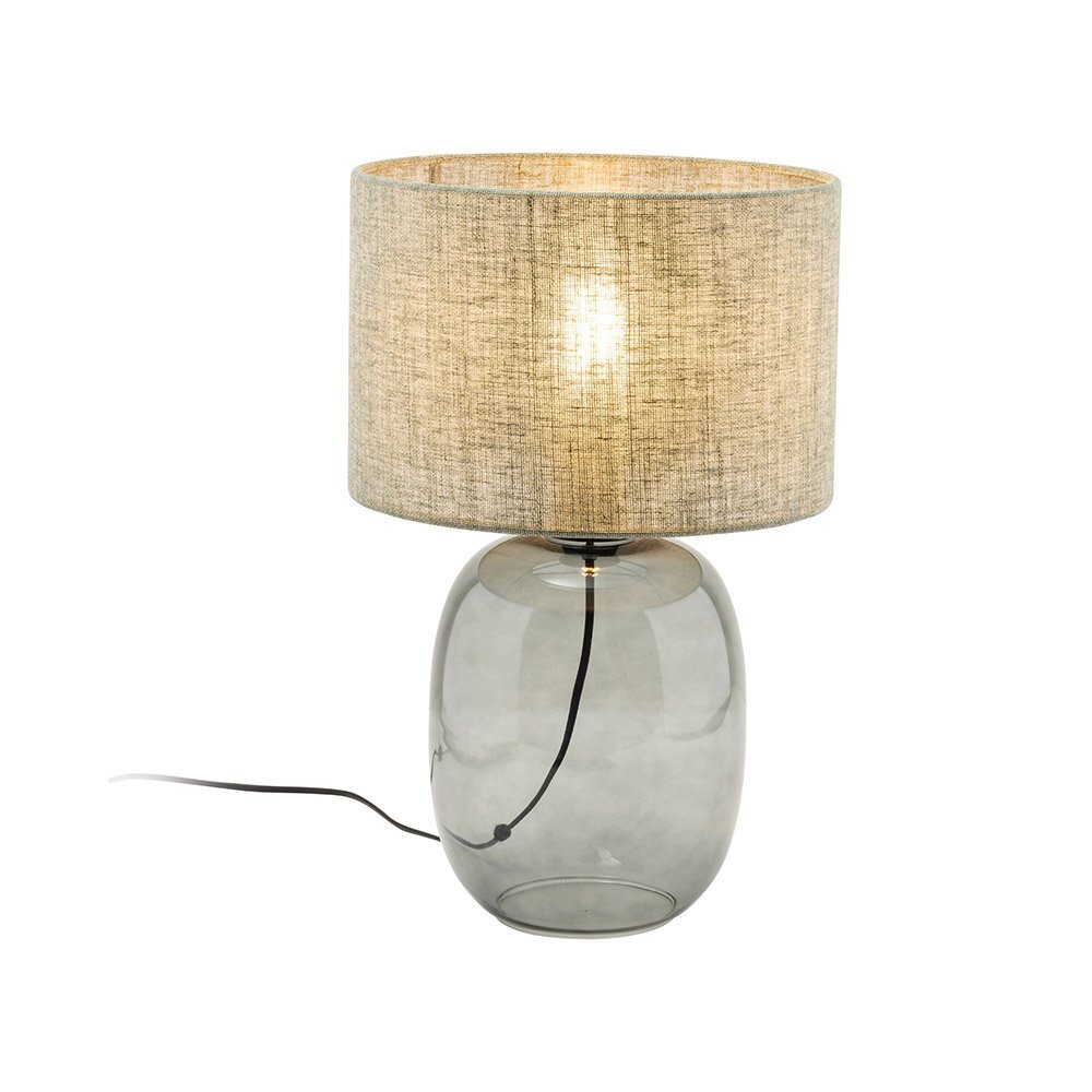 Lampa stołowa z przezroczystą, szklaną podstawą i cylindrycznym abażurem w kolorze beżowym. Kabel zasilający jest widoczny i wychodzi z podstawy lampy.