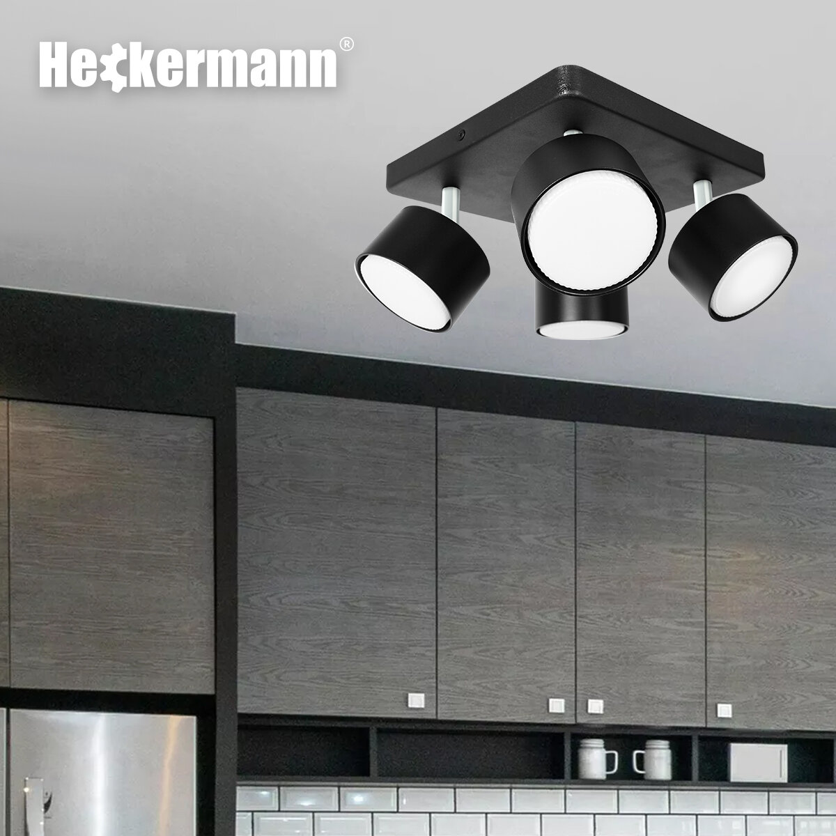 Czarna lampa punktowa LED z czterema głowicami zamontowana na suficie. W tle widoczne są szafki kuchenne i logo \'Heckermann\'.