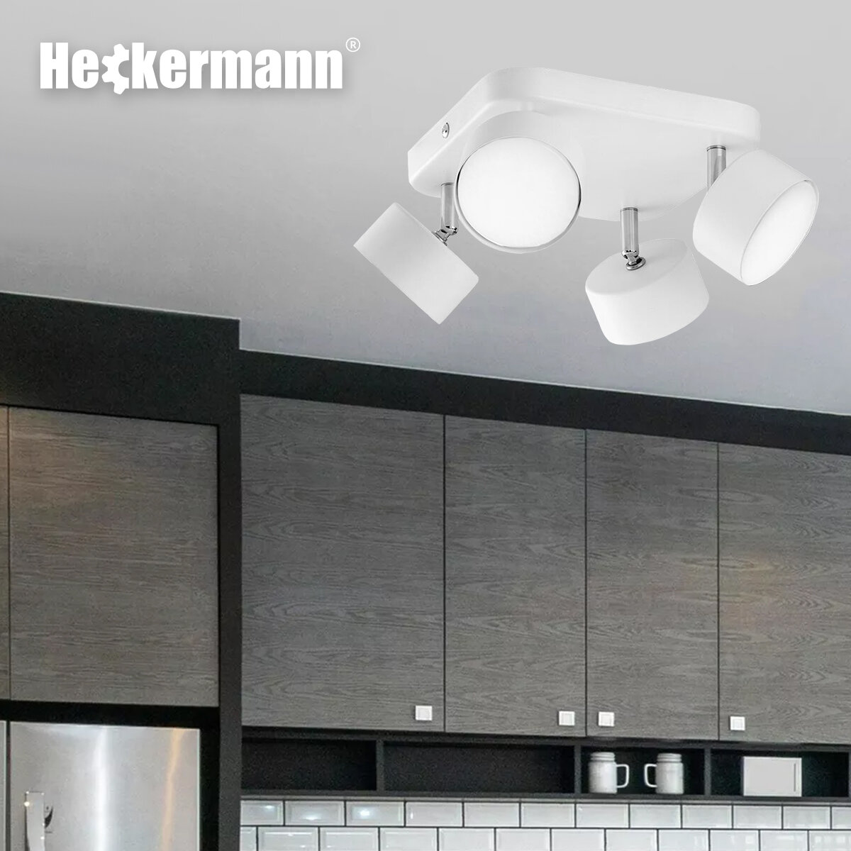 Na obrazie widoczna jest biała lampa punktowa z czterema głowicami zamontowana na suficie. W tle znajdują się szafki kuchenne, a w lewym górnym rogu widnieje logo \'Heckermann\'.