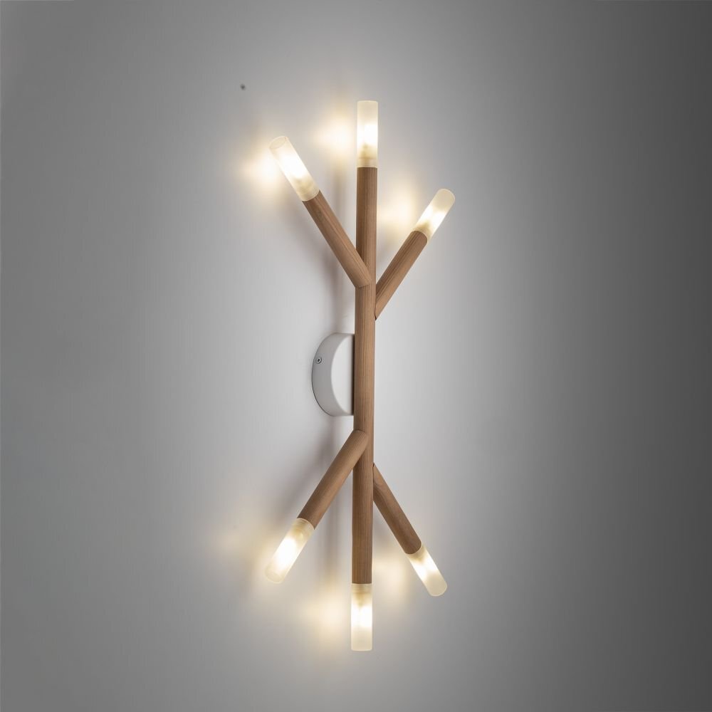 Lampa ścienno-sufitowa o nowoczesnym designie, wykonana z metalu i drewna sosnowego, z sześcioma źródłami światła w kształcie gałęzi. Światło jest ciepłe i rozproszone, a całość zamontowana jest na ścianie.