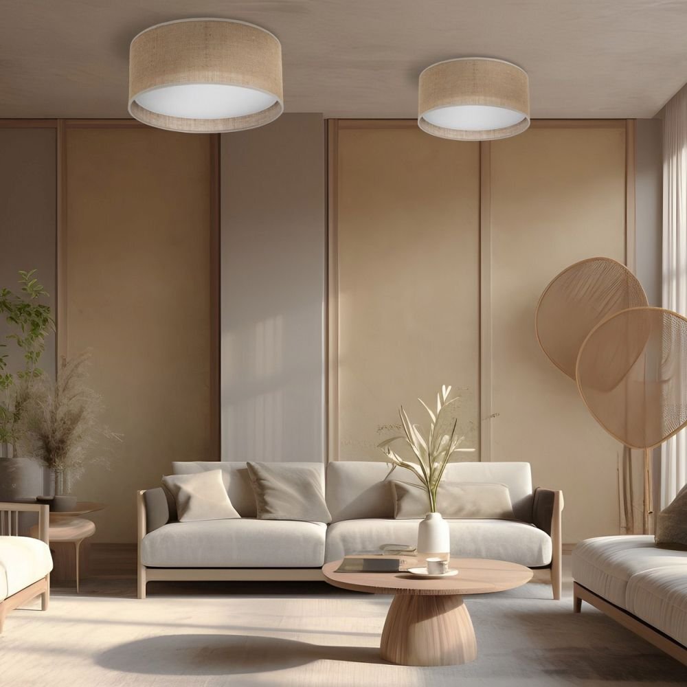 Wnętrze salonu z dwoma lampami sufitowymi o cylindrycznym kształcie, wykonanymi z białego materiału z jutą. W pomieszczeniu znajdują się jasne meble, w tym sofa, stolik kawowy i dekoracyjne rośliny.