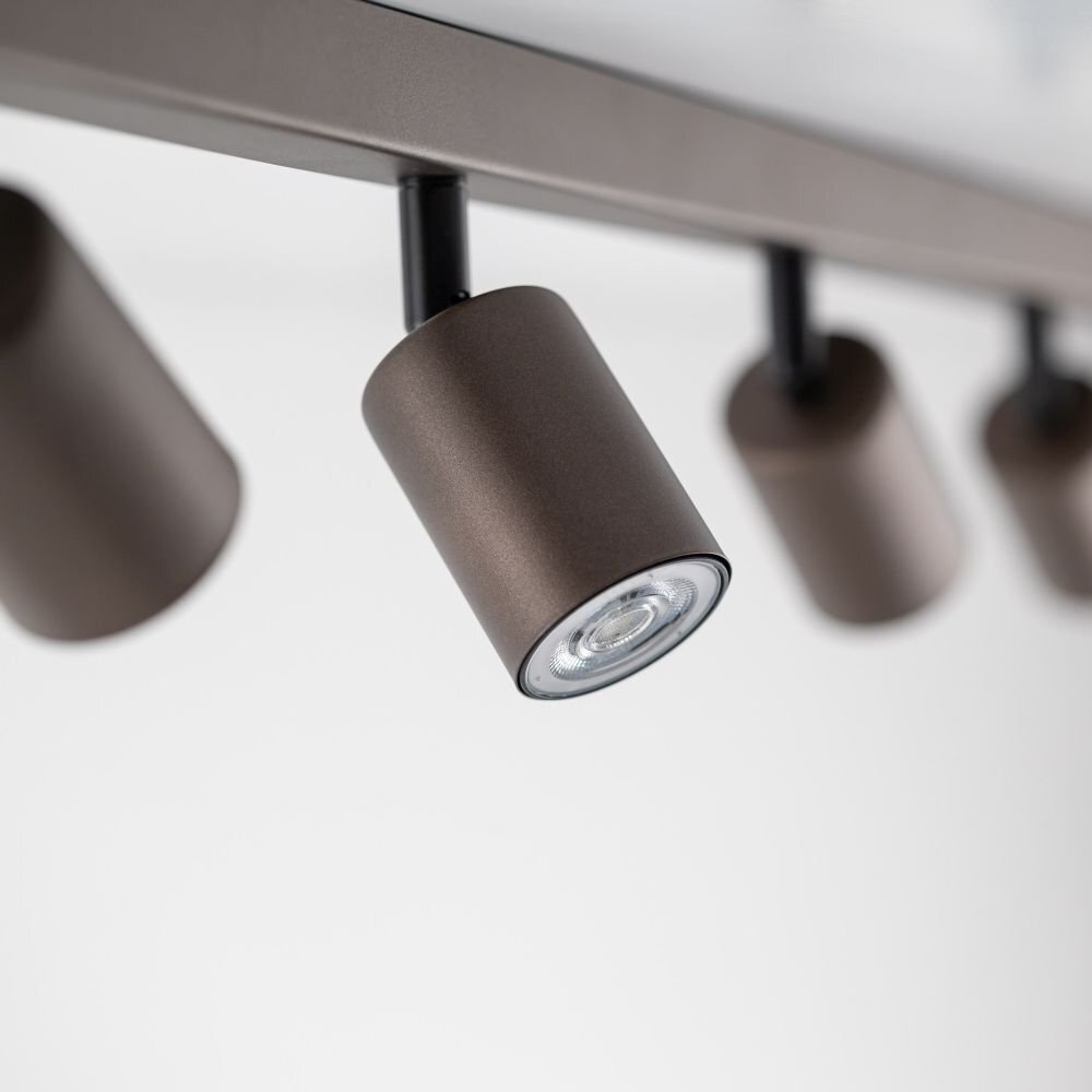 Brązowa lampa sufitowa z kilkoma reflektorami zamontowanymi na listwie. Reflektory są cylindryczne i mają regulowane położenie.