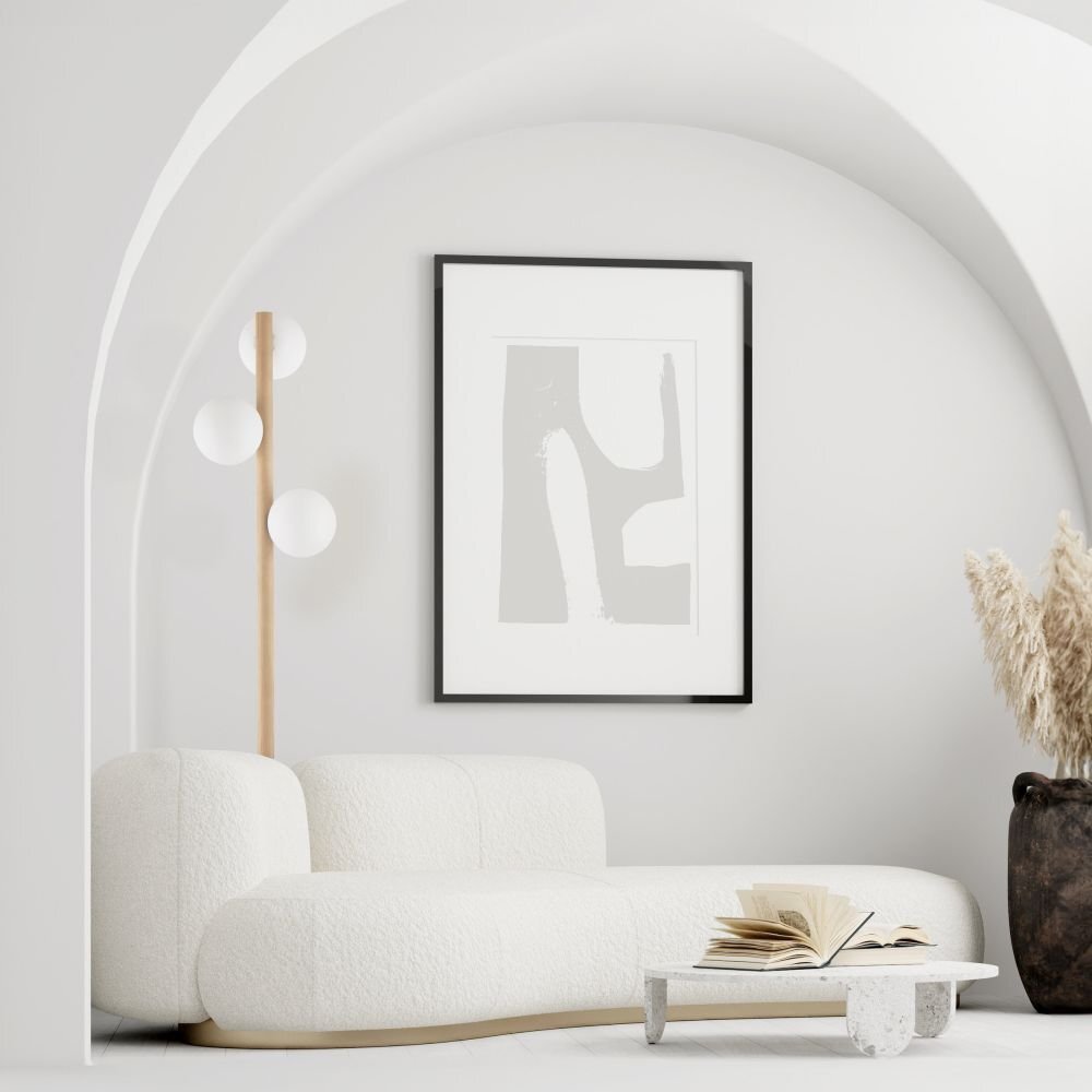 W jasnym, minimalistycznym wnętrzu znajduje się biała sofa, obok której stoi lampa podłogowa z trzema kulistymi kloszami na drewnianym stelażu. Na ścianie wisi abstrakcyjny obraz w czarnej ramie, a na niskim stoliku leży otwarta książka.
