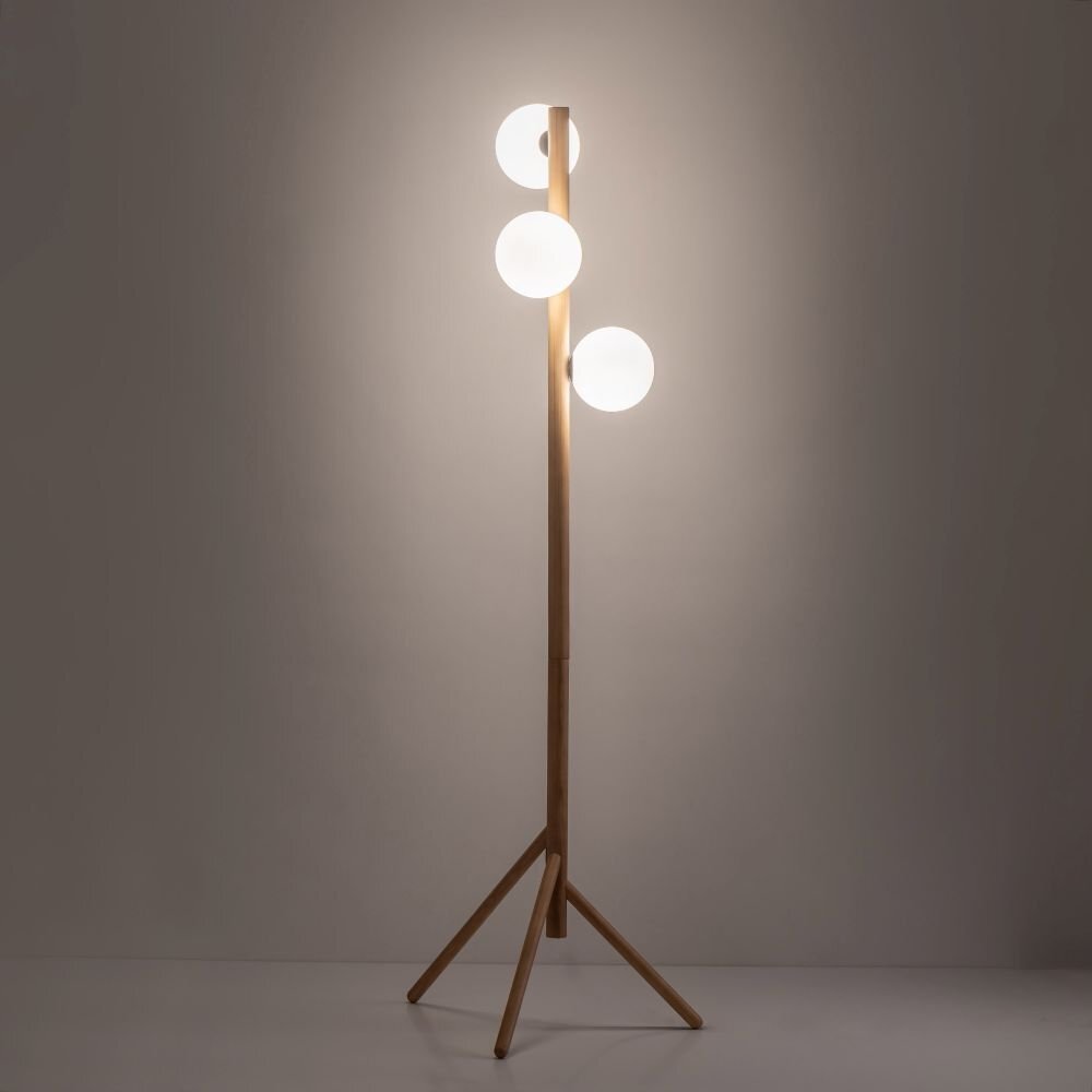 Lampa podłogowa z trzema kulistymi kloszami na drewnianym stojaku. Klosze są białe, a stojak wykonany z jasnego drewna.