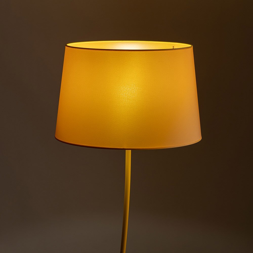 Żółta lampa podłogowa z metalowym stelażem i abażurem o prostym, klasycznym kształcie. Tło jest jednolite i ciemne, co podkreśla kolor lampy.